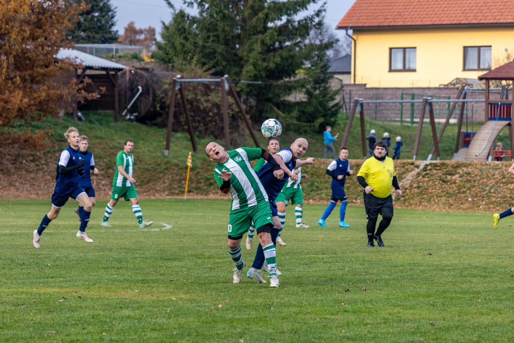 Dva fotbalisté hlavičkují míč v souboji před brankou.