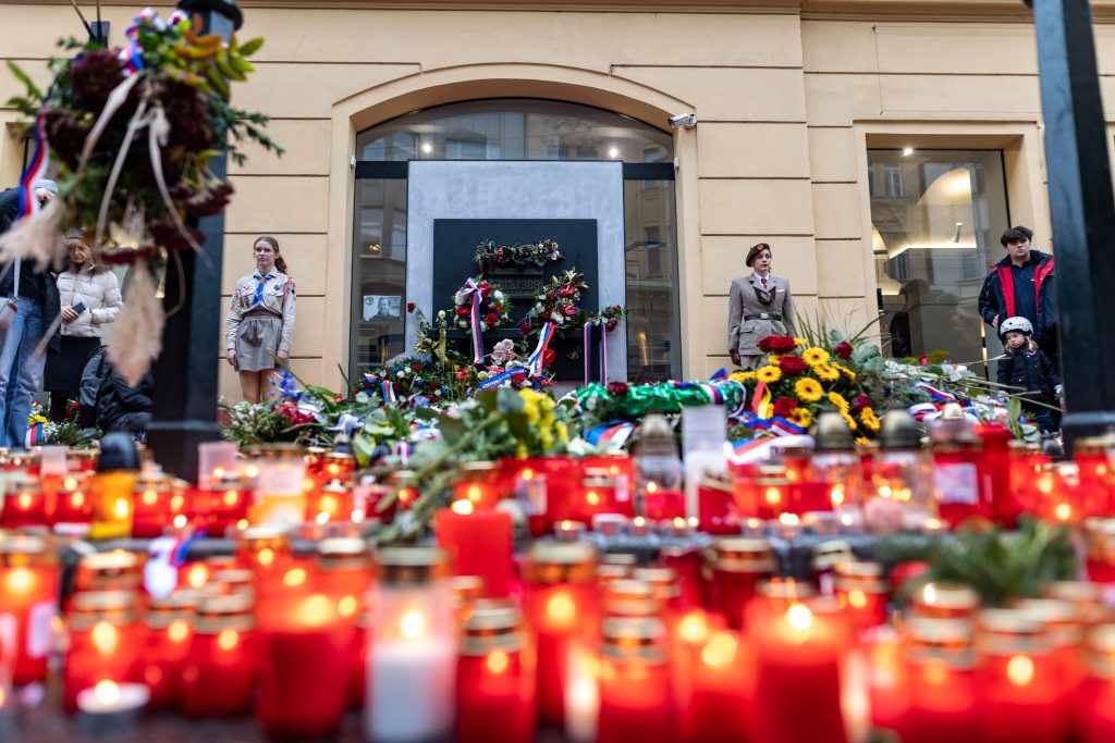 Hořící svíčky, květiny a věnce položené u pamětního místa v centru Prahy.