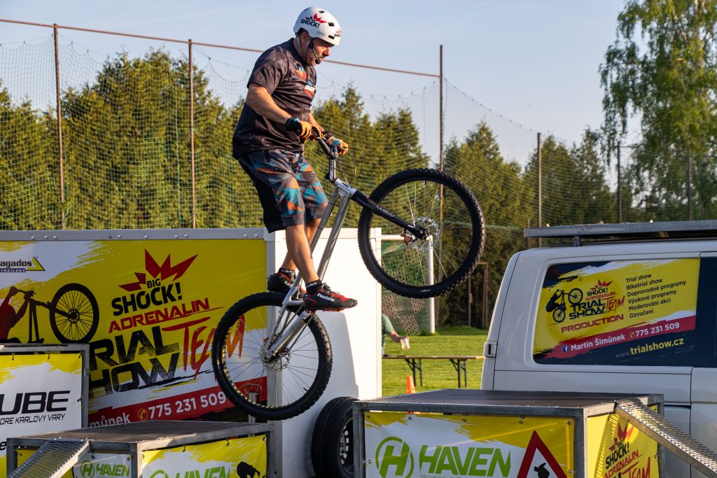 Cyklista v helmě balancuje na zadním kole během trialové exhibice.